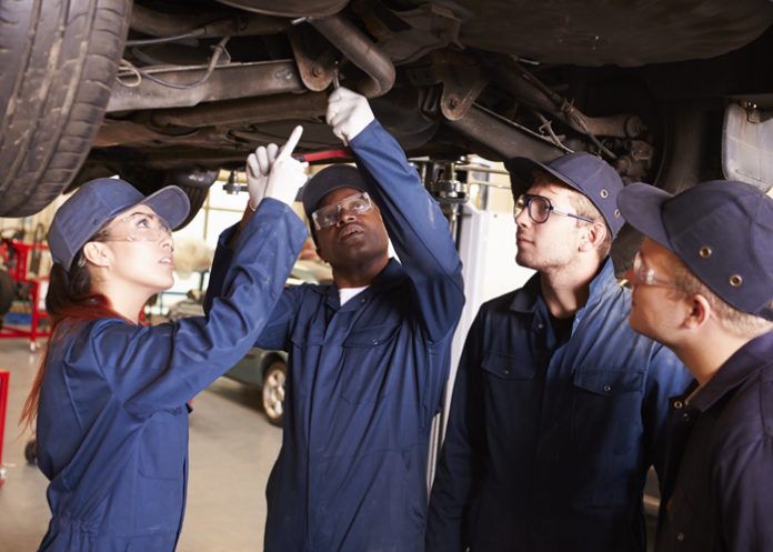 Teacher Helping Students Training To Be Car Mechanics